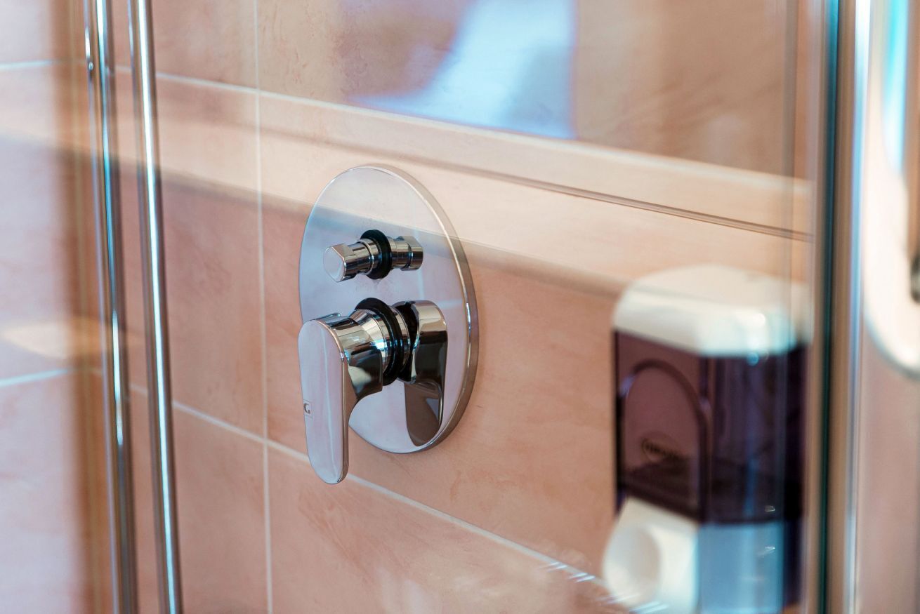 Une salle de bain avec une douche à parois de verre, un robinet chromé et un miroir.