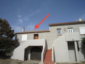 Un bâtiment doté d’une grande entrée en arc de cercle, d’une petite porte et d’un escalier menant à un deuxième étage.