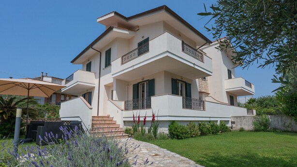 A two-story house with a balcony, a stone pathway, and a garden with lavender. - Villa Minerva Sperlongaresort (Sperlonga)