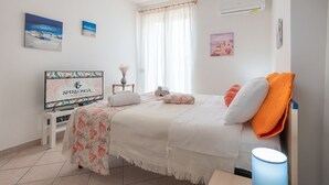 A hotel room with a bed, a TV, a desk, and a window with curtains. - Villa Minerva Sperlongaresort (Sperlonga)