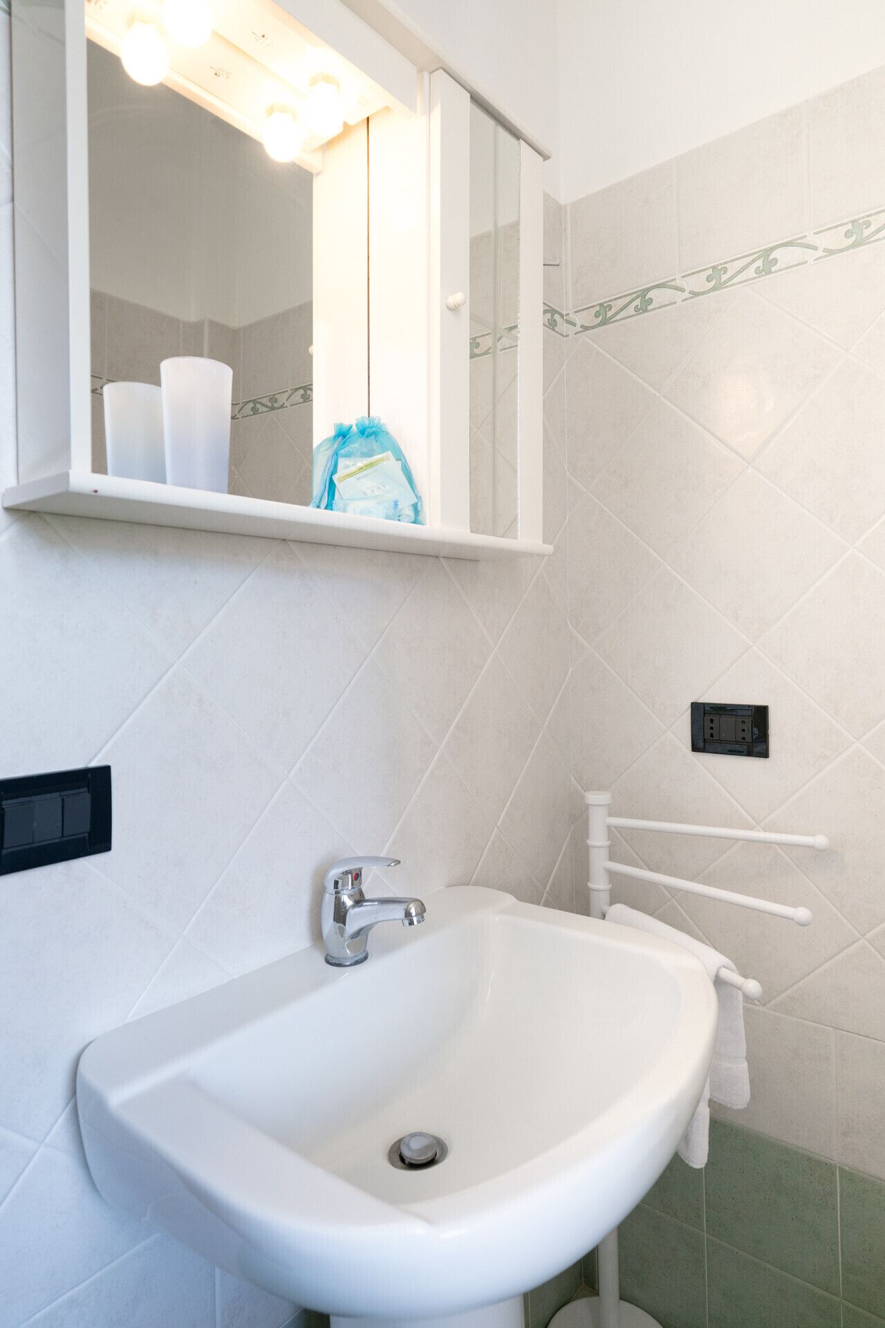 A bathroom with a white sink, a mirror, and a towel rack.