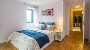 Ein Schlafzimmer mit einem Bett, einem Nachttisch, einem Fenster und einer Tür zu einem Badezimmer.