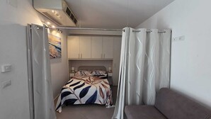 Une chambre à coucher comprenant un lit, un canapé, une armoire et un ventilateur de plafond.