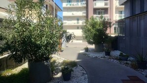 Un chemin menant à un immeuble résidentiel à plusieurs étages, doté de balcons.