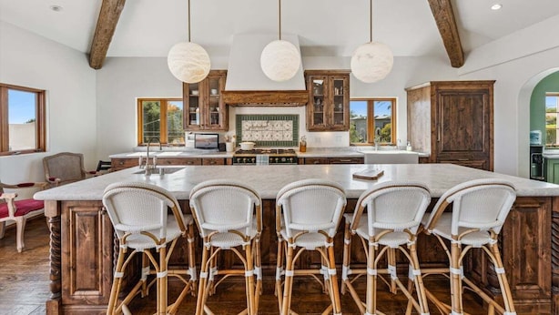 A spacious kitchen with a large island, wooden cabinets, and hanging pendant lights.