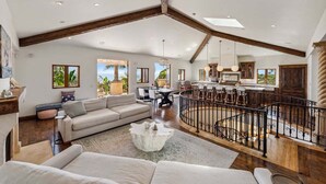 A spacious living area with a high ceiling, a dining area, and a kitchen.