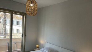 A bedroom with a bed, a window, and a hanging light fixture. - 3-Room Apartment Air-Conditioned, Sea View, Downtown Le Lavandou (Le Lavandou)