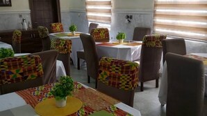 Comedor con mesas cubiertas por manteles coloridos, sillas y plantas en macetas.
