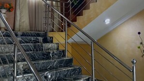 Una escalera de mármol con barandillas metálicas que baja a un nivel inferior.