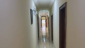 Un pasillo largo y estrecho con piso de baldosas brillantes, puertas a ambos lados y una lámpara en el techo.