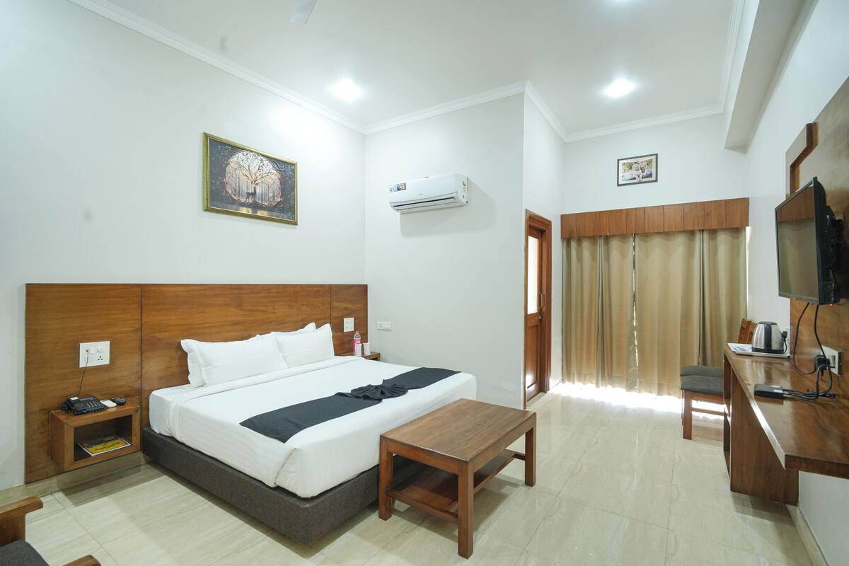 Una habitación de hotel con cama, mesita de noche, escritorio, silla y aire acondicionado.