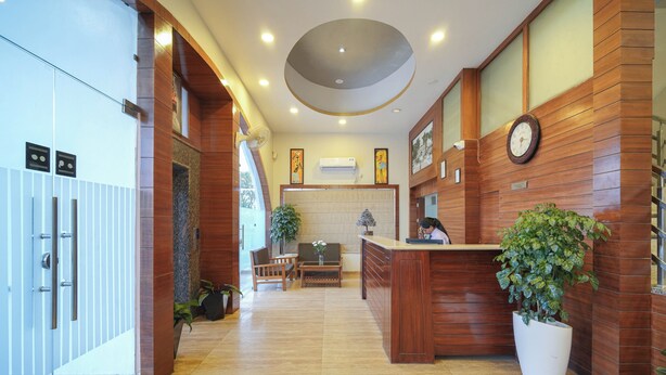 Un espace d’accueil avec un comptoir en bois, une horloge et une plante en pot.