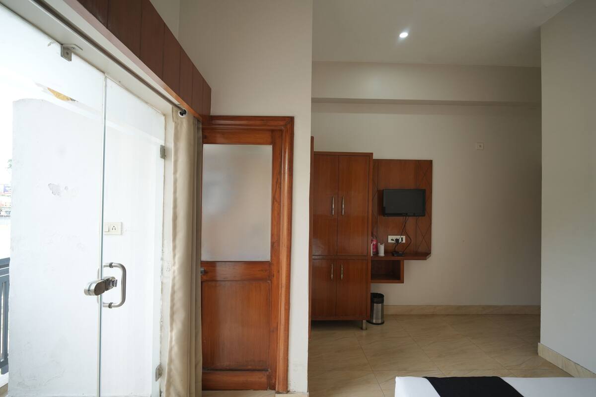 Un interior con una puerta blanca, armarios de madera, un televisor montado en la pared y un cubo de basura.