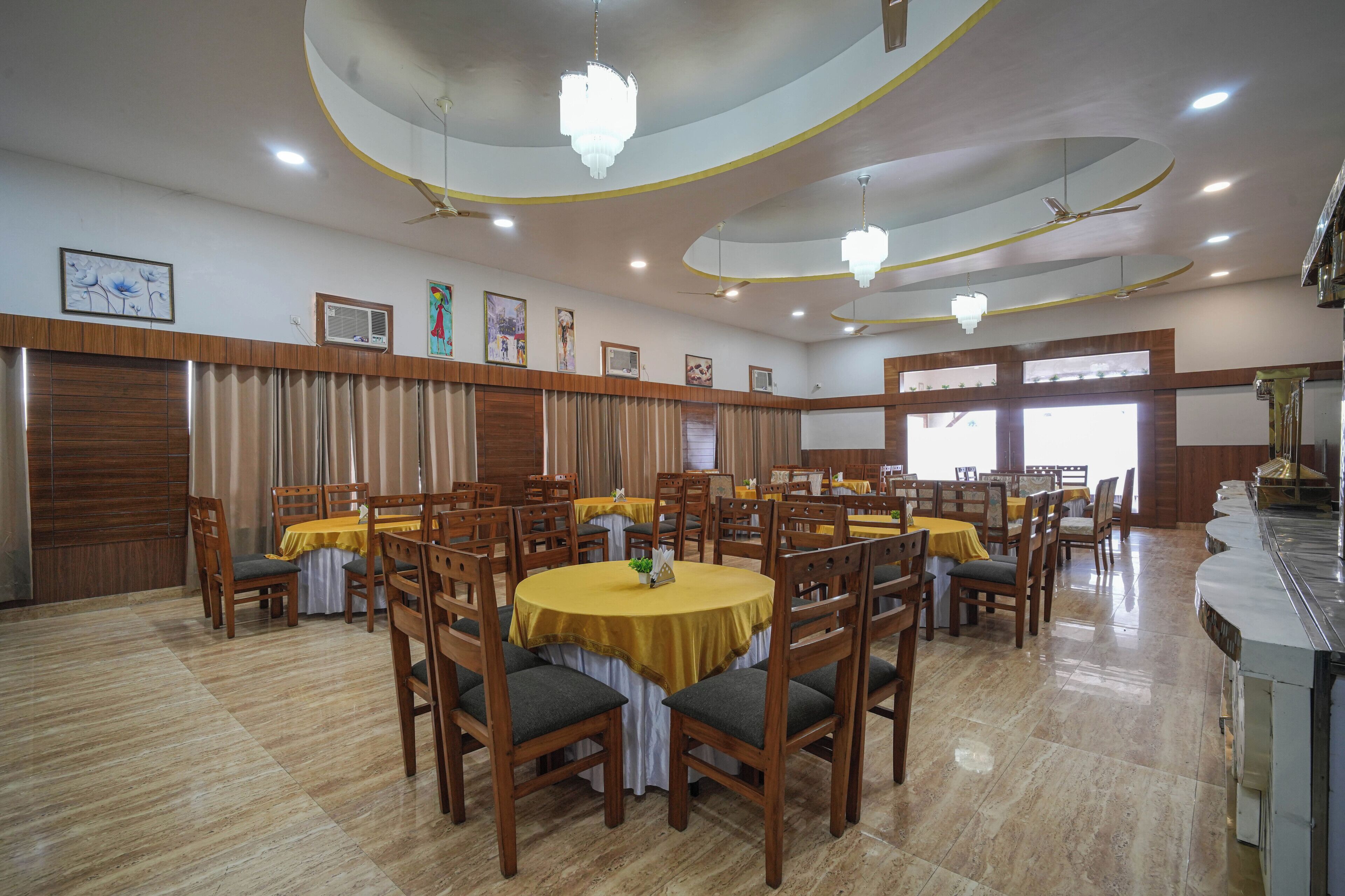 A spacious dining area with round tables, wooden chairs, and a modern ceiling design.