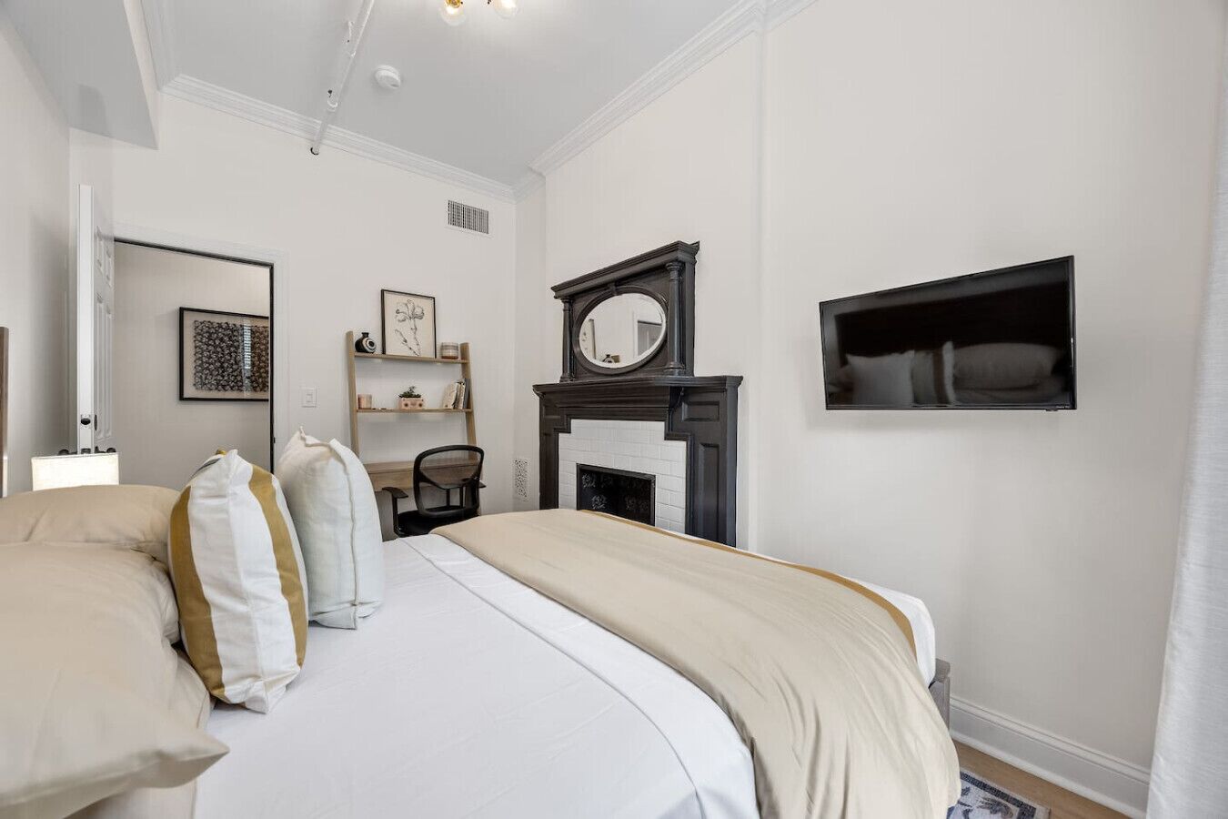 Une chambre à coucher avec un grand lit, un bureau, une chaise, une cheminée et un miroir au mur.