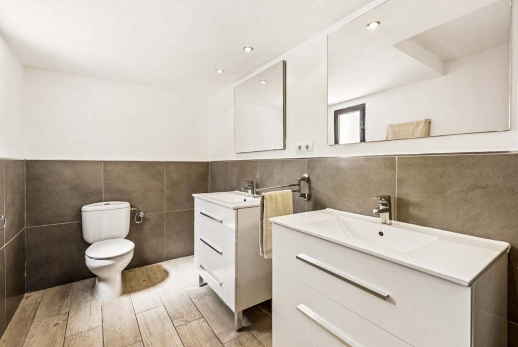 Une salle de bain moderne équipée de toilettes, d’un meuble-lavabo et d’un miroir.
