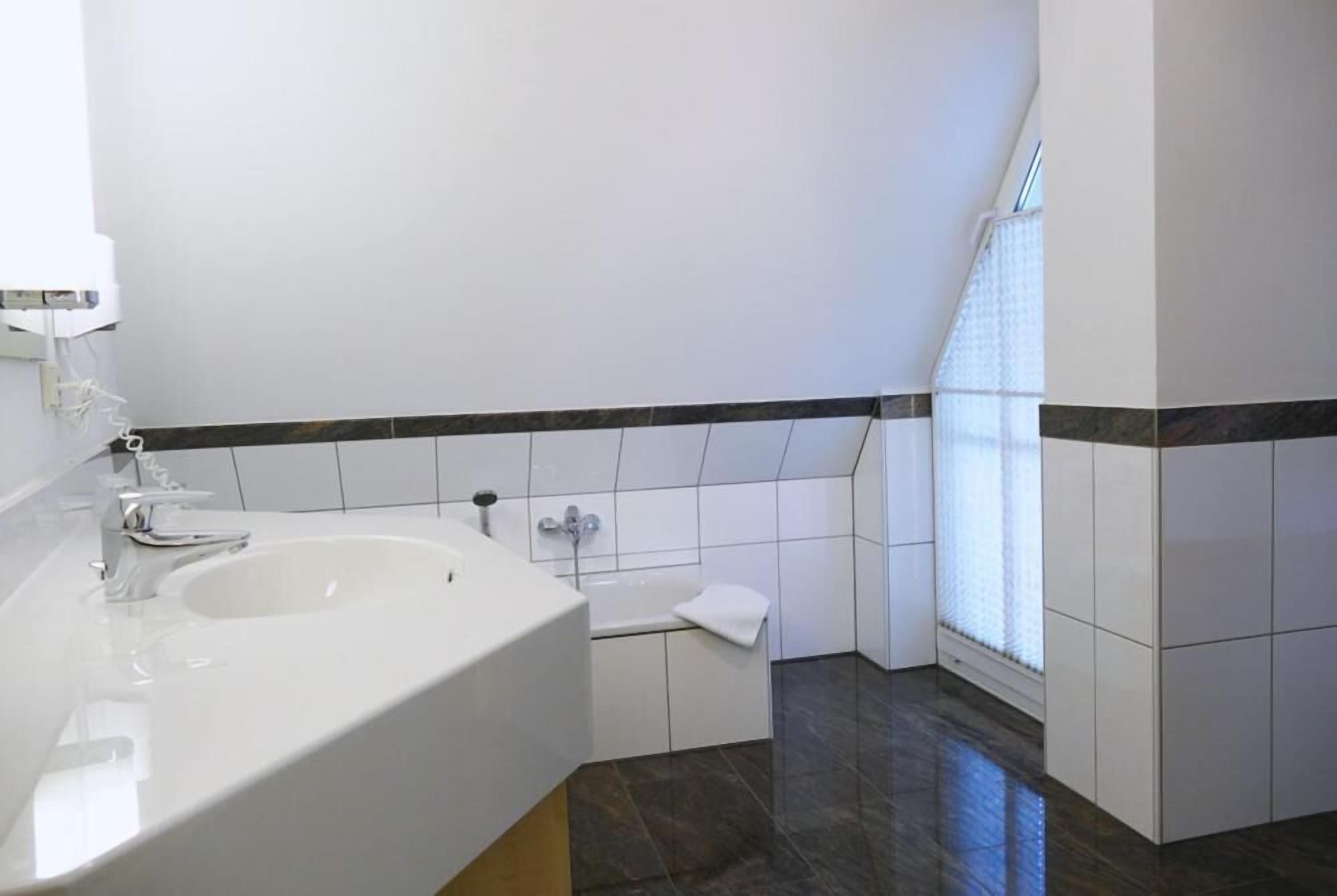 A modern bathroom with a large sink, a bathtub, and a toilet.