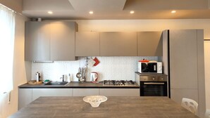 Una cocina moderna con armarios grises, un microondas, una estufa a gas y una mesa de comedor con un centro de mesa de cristal.