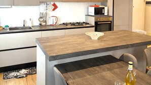 Una cocina moderna con una isla central, electrodomésticos integrados y un comedor con mesa y sillas.