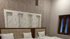 Een hotelkamer met twee bedden, muren met een marmerlook en een groot raam met tralies.