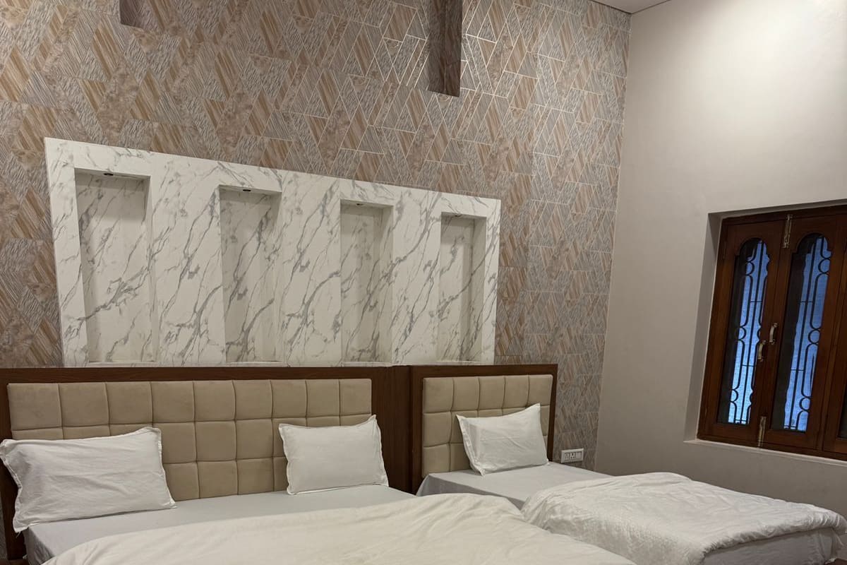 Habitación de hotel con dos camas, paredes con diseño de mármol y un ventanal con barrotes.