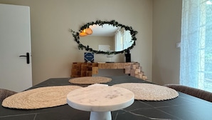 A modern living room with a round white coffee table, woven mats, a mirror, and a decorative wreath on the wall.