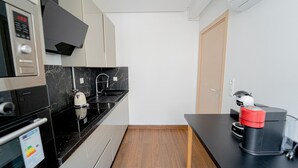 Eine kleine Küche mit schwarzem Arbeitsplatz, einer Kaffeemaschine und einer Mikrowelle.