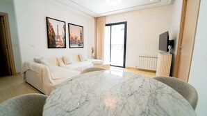 Ein modernes Wohnzimmer mit einem Esstisch aus Marmor, einer Couch und zwei gerahmten Bildern bekannter Wahrzeichen.
