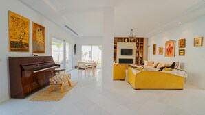 A spacious living room with a piano, yellow sofa, and a TV. - La Marina Secure Seaside With Pool (La Marsa)
