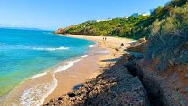 A coastal beach with clear blue waters, a sandy shore, and rocky cliffs. - La Marina Secure Seaside With Pool (La Marsa)