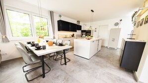 Una cocina moderna con comedor, ventanas amplias y una pequeña isla.