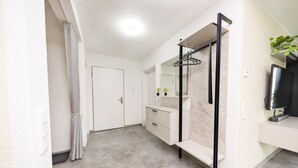 Un baño moderno con ducha, espejo, lavabo y televisor.