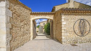 A narrow cobblestone alleyway with stone walls and an arched entrance leading to a building. - Mas Cicada (Paradou)