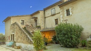 A historic building with a stone staircase, a small outdoor seating area, and potted plants. - Mas Cicada (Paradou)