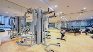 A gym with various exercise equipment, including weight machines and dumbbells. - Beautiful Studio with balcony in JVC (Dubai)