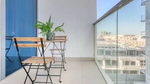 A balcony with a table and chairs, a potted plant, and a city view. - Beautiful Studio with balcony in JVC (Dubai)