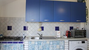 A kitchen with blue cabinets, a gas stove, a sink, a toaster, and a washing machine. - "House Kalavriya" 50mt from the sea (Nicotera Marina)
