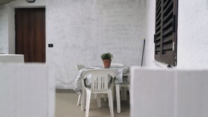 A small, enclosed patio area with a table and chairs, a potted plant, and a door. - "House Kalavriya" 50mt from the sea (Nicotera Marina)