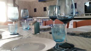 A dining area with a table set for two, featuring a patterned tablecloth, a white plate, and two wine glasses. - "House Kalavriya" 50mt from the sea (Nicotera Marina)