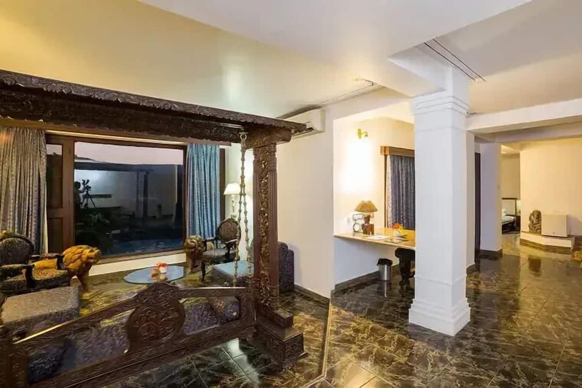 Un amplio vestíbulo de hotel con piso de mármol, un ventanal con cortinas y una zona de estar con mesa y sillas.