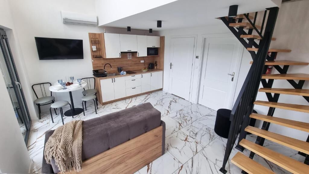 A modern kitchen with white cabinets, a wooden countertop, and a black microwave.