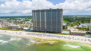 A high-rise hotel with multiple floors, a beachfront location, and a pool area. - Sapphire Shores - Beachfront With Chair Setup (Panama City Beach)