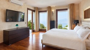 A bedroom with a bed, a TV, a dresser, and a view of the outdoors.