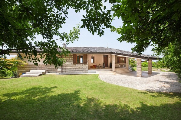 A stone house with a tiled roof, a covered patio, and a well-maintained lawn. - Villa Viù with Pool and Lake View (Torri del Benaco)