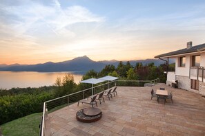 A patio with outdoor furniture, a fire pit, and a view of a lake and mountains.