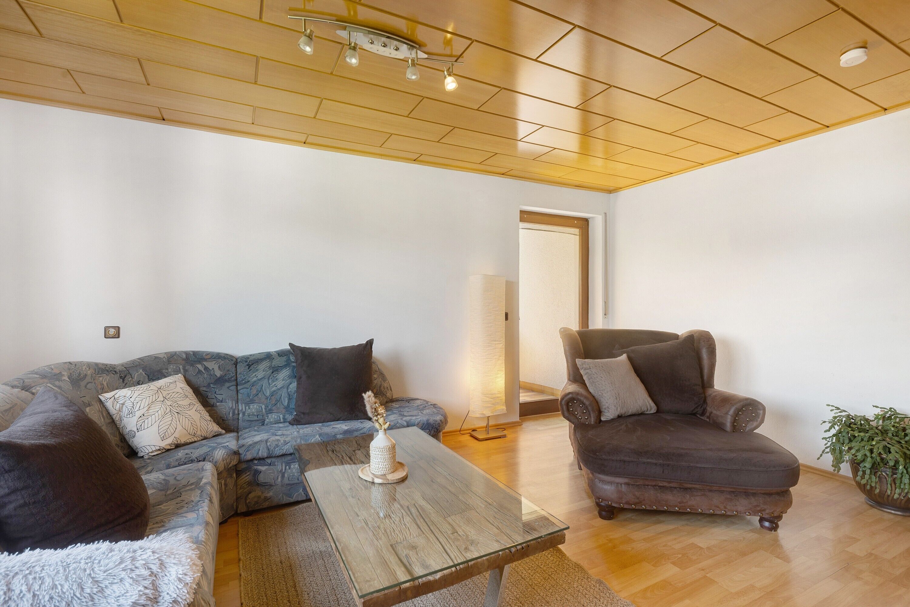 Un salon comprenant un canapé, un fauteuil, une table basse et une lampe.