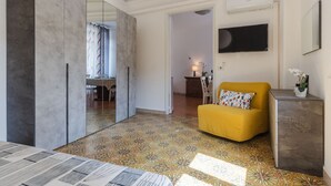 A modern living room with a yellow sofa, a small cabinet, and a TV mounted on the wall. - A Casa di Silvia by Wonderful Italy (Catania)