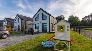 A modern residential area with a playhouse, a car, and a patio with outdoor furniture. - ZATOR Domki INTERSTYL (Zator)