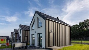 A modern building with a large entrance, a bench outside, and a grassy area. - ZATOR Domki INTERSTYL (Zator)
