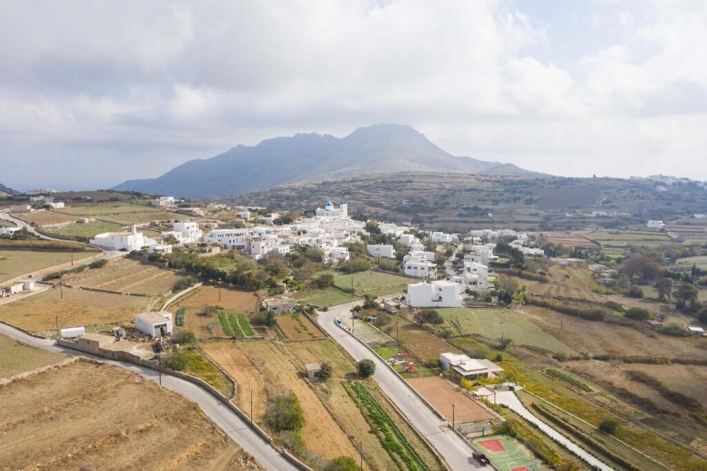 Un borgo costiero con edifici bianchi, una strada e campi coltivati.